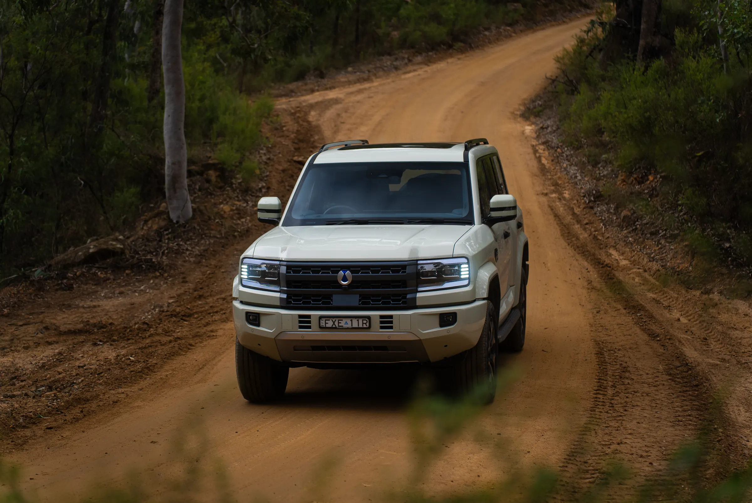 DENZA B5 Leopard driving front-on along a winding dirt road through Australian bushland
